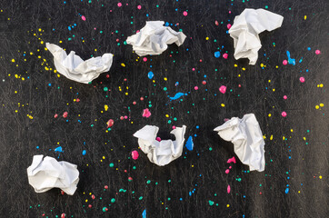 Chaotic drops of paint and pieces of paper on black texture.