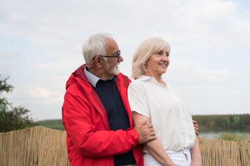 A good-looking senior couple is walking through the garden and enjoying the view.