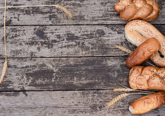 Fresh crispy bread with spikelets of wheat on wooden background table. Copy space for text, top...