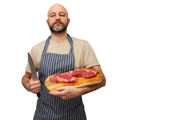 Bald butcher holding wooden cutting board with two fresh strip loin steaks. Meat industry. White isolated background. Prime cut of steak. The model is in t shirt and black and white apron,