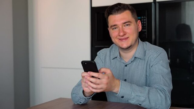 Young confident man typing smart phone then looking to the Camera confidently. Portrait of young Caucasian 30s Man with regular look. Using Smartphone. Social Network. Work indoors. Success. People