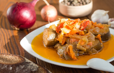 vegetable stew with eggplant in its own orange juice on a white plate