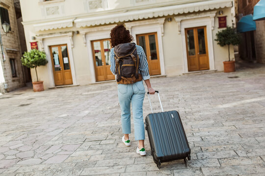 Young woman with suitcase in old city on vacation