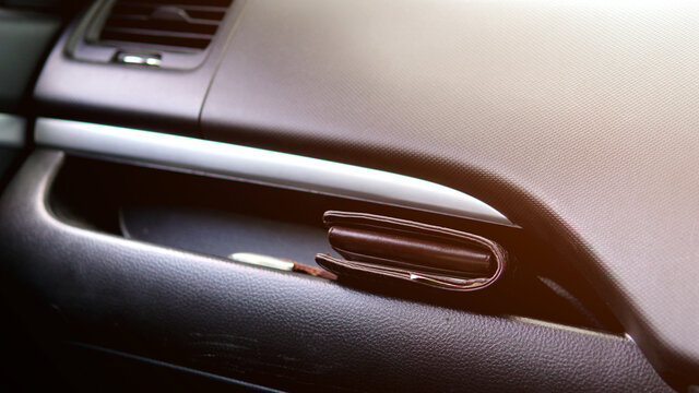 Brown leather wallet placed in front of the car.