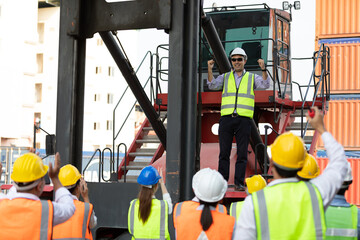 warehouse boss engineer standing on crane car with factory workers raise hand for congratulations in containers warehouse storage