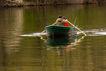 Fototapeta na wymiar zwei Angler Männer rudern in einem Boot auf einem See