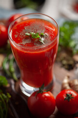 Close-up of Indian Homemade fresh and healthy tomato soup garnished with fresh coriander leaves and ingredients and herbs, served in a glass over the wooden top background. 