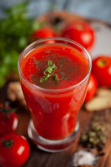 Close-up of Indian Homemade fresh and healthy tomato soup garnished with fresh coriander leaves and ingredients and herbs, served in a glass over the wooden top background. 