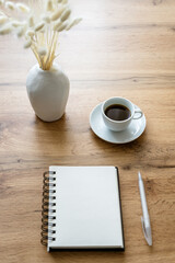 Ein leerer Spiralblock und eine Tasse Kaffee auf einem Holz Tisch. Kaffeepause, minimalistisch.