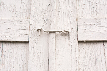 Old white wooden door, closed on a metal hook. Close-up. Vintage