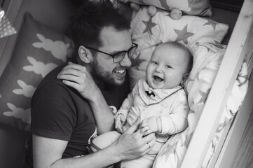 Portrait of cute baby boy with father in his house bed. Happy childhood