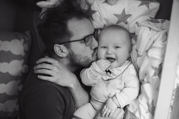 Portrait of cute baby boy with father in his house bed. Happy childhood