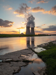 Nuclear power plant against sky by the river at sunset