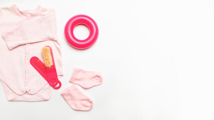 Flat lay composition. Child accessories. baby clothes for girl. Set with bodusuit and socks, hairbrush, toy on white background. Space for text