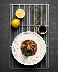 Grilled chicken wings with lemon and rosemary. Hearty lunch, cooked poultry. Top view on black background. Vertical format, 4x5.