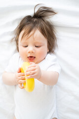 cute baby boy lying on bed and play with yellow plastic circle toy.