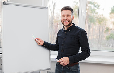 Cheerful male manager standing near whiteboard in office