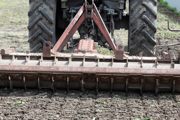 The tractor cultivates the soil in the spring with a cultivator.