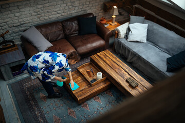 Asian woman dusting in living room