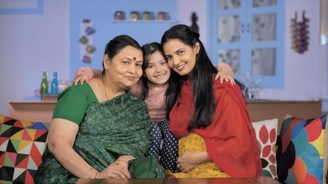 Cute little girl hugging her mother and grandmother to pose for the camera. Medium shot of an adorable three generations women spending their weekend together - family bonding 