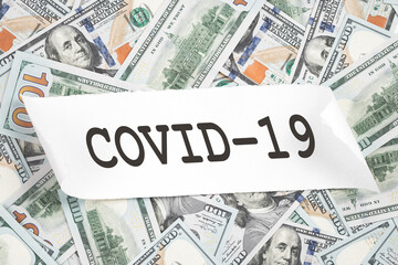 Covid-19 text over lots of us dollar bills. Coronavirus C-19 costs vaccination