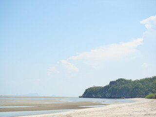 Beach with sand and mud in water phenomenon at low tide, Ocean waves splash the shore severely , Bay with mountain at Khao Sam Roi Yot national park , Thailand