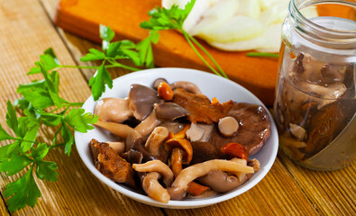 Various pickled mushrooms in plate with onions and parsley