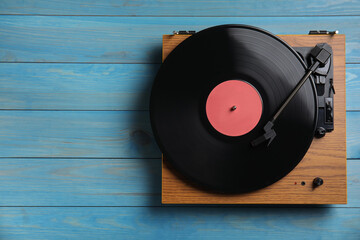 Modern vinyl record player with disc on blue wooden background, top view. Space for text