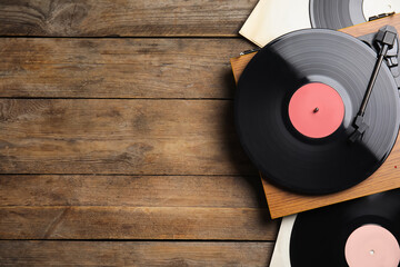 Modern player and vinyl records on wooden background, flat lay. Space for text - obrazy, fototapety, plakaty