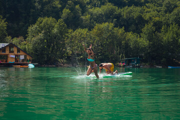 Couple having fun stand up paddling together on lake