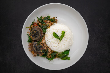 Khao Pad Ka Prao Kai Yeow Ma, Thai food, streamed rice with basil stir fried century egg and mince pork in ceramic plate on dark grey texture background