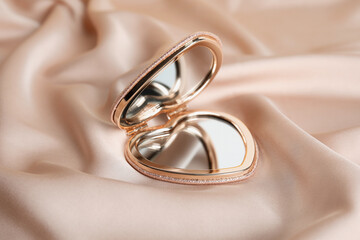 Stylish heart shaped cosmetic pocket mirror on rose gold fabric