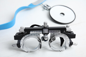 Trial frame and head mirror on white wooden table, closeup