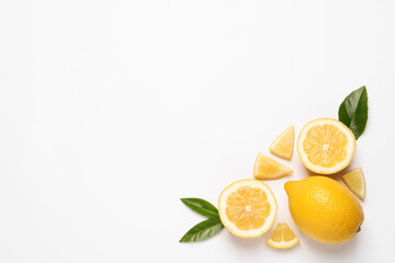 Flat lay composition with fresh juicy lemons and green leaves on white background. Space for text