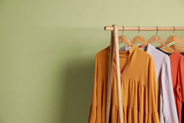 Collection of trendy women's garments on rack near green wall, space for text. Clothing rental service