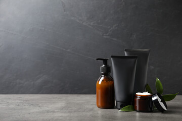 Facial cream and other men's cosmetic with green leaves on grey stone table. Mockup for design