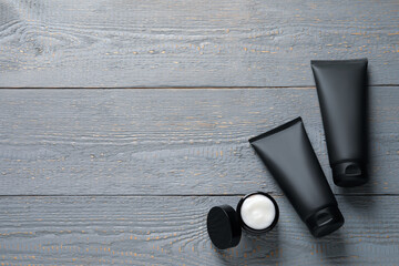 Tubes and jar with men's facial creams on grey wooden table, flat lay. Mockup for design