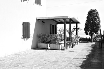 A patio with a wooden gazebo surrounded by plants and flowers (Fiorenzuola di Focara, Marche, Italy)