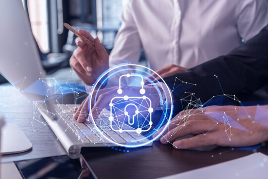 Two businesspeople in formal wear working on the project to protect cyber security of international company using laptop. Padlock Hologram icons. Teamwork concept.