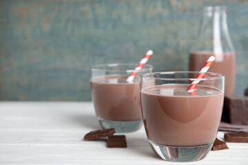 Delicious chocolate milk on white wooden table. Space for text