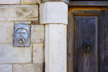 An ancient decoration set between the stones of a wall and a door of an old house.