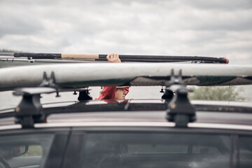Fototapeta na wymiar Windsurfer and camper packing and unpacking from a car's roof rack in nature.