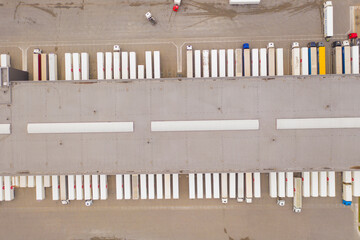 Aerial view of goods warehouse. Logistics delivery  center in industrial city zone from above. Aerial view of trucks loading at logistic center. View from drone.