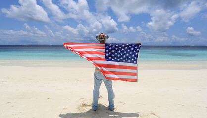 4th of July, Independence Day of the USA, a man with the American Flag on the shore of a tropical island