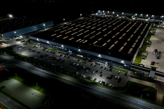 Night Aerial view of goods warehouse. Logistics center in industrial city zone from above. Aerial view of trucks loading at logistic center. View from drone.