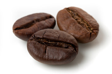 Three grains of black arabica coffee on an isolated white background. Macro photo.