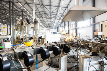 Workshop with extruders for producing plastic pipes. High speed extrusion line of water suppply and gas pipe. Manufacturing facility.