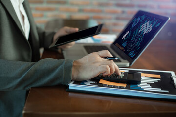 Female businessman working with holding a pen and using a calculator to calculate the numbers of...