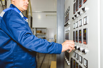 A worker presses a button and starts an automatic manufacturing process in a factory