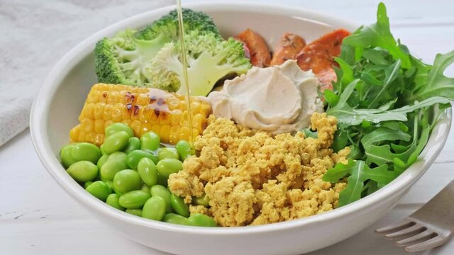 Vegan breakfast bowl - scrambled tofu, corn, beans, sweet potato and broccoli. Plant-based diet concept.